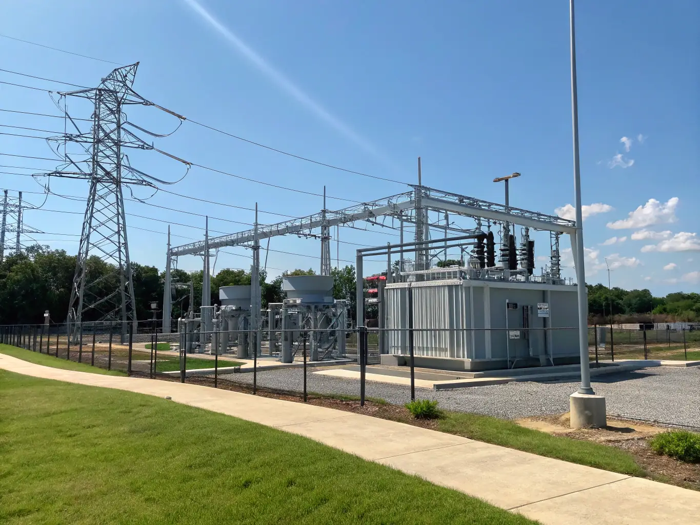 A photograph of a modern electrical substation with advanced monitoring equipment, set against a clear blue sky.
