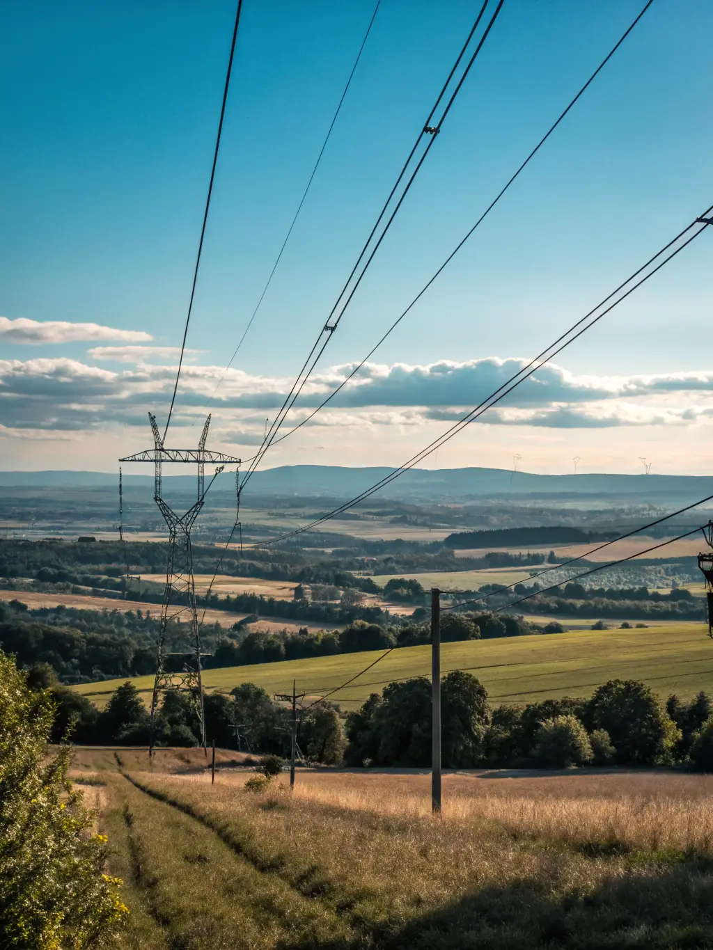 High-voltage power lines stretching across a rural landscape, illustrating REGIONTEL & CelinTech's expertise in electric and power solutions.